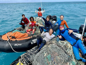 PMDP crew sitting on commercial fishing nets and other marine debris they pulled out of the ocean.